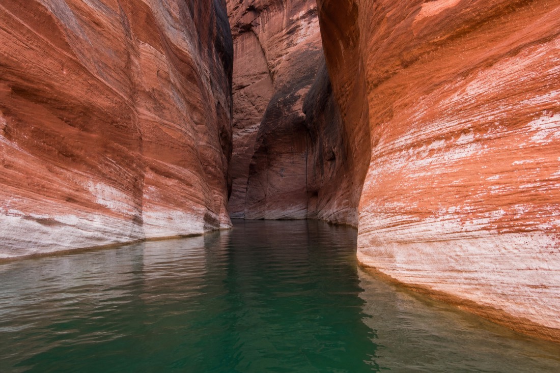 A guided kayak group on calm green water between the canyon walls of Antelope Canyon's Lake Powell arm