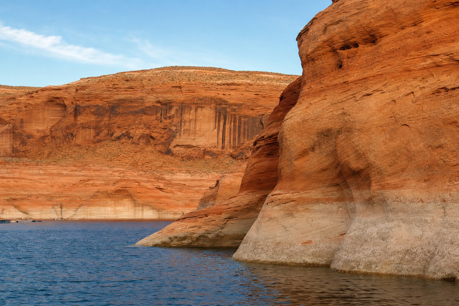 Calm blue water of Lake Powell meeting orange sandstone cliffs near Antelope Point