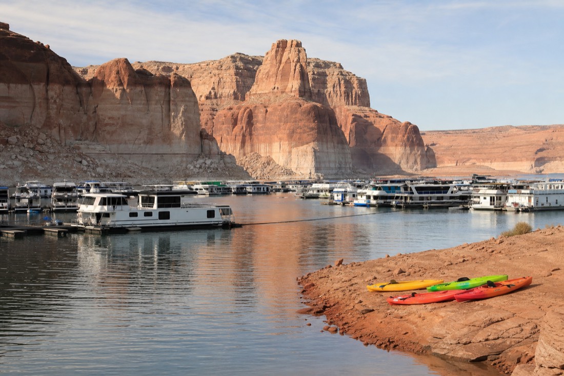 Marina area on Lake Powell with houseboats and kayaks against high desert cliffs