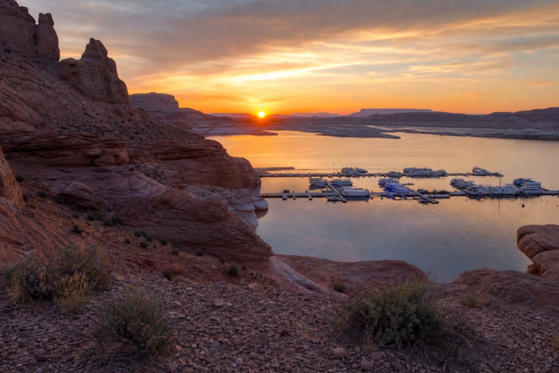 Sunset over Lake Powell with warm light on sandstone and a quiet marina in shadow