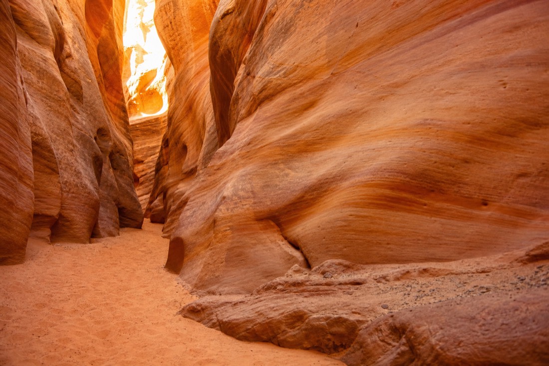 Sunlit sandstone textures inside a quiet slot canyon with layered orange and gold bands