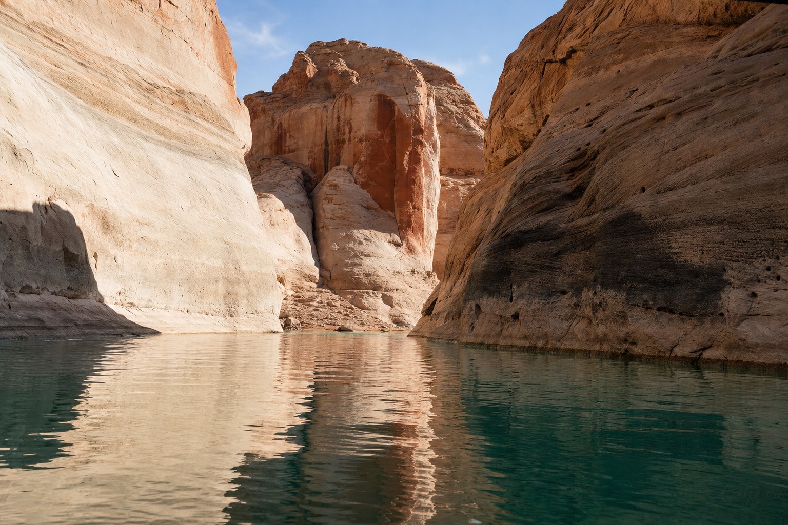 Kayaker paddling calm turquoise water between tall sandstone cliffs on Lake Powell
