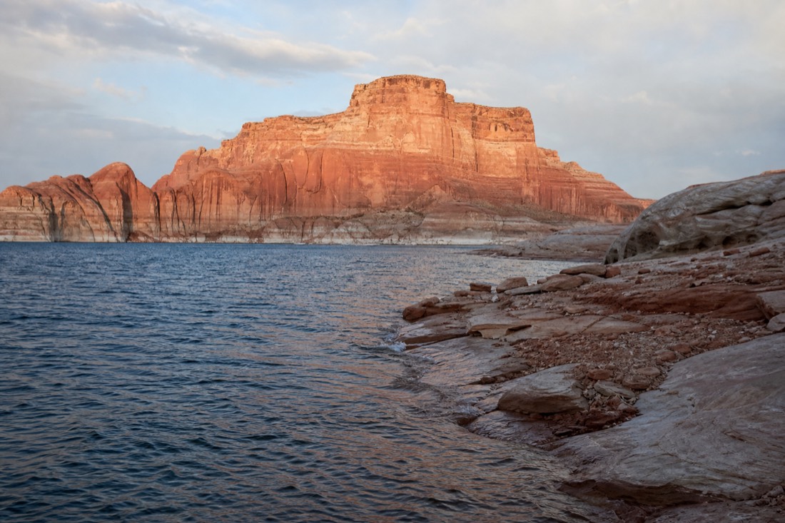 Wide view of Lake Powell shoreline where national recreation area water meets desert cliffs