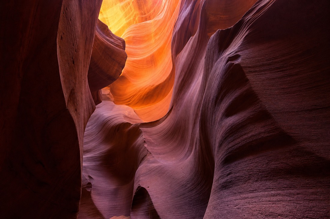 Sculpted sandstone waves glowing orange and violet inside Lower Antelope Canyon