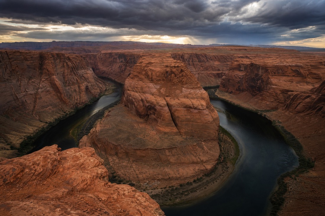 Horseshoe Bend overlook with the Colorado River curving under moody storm light
