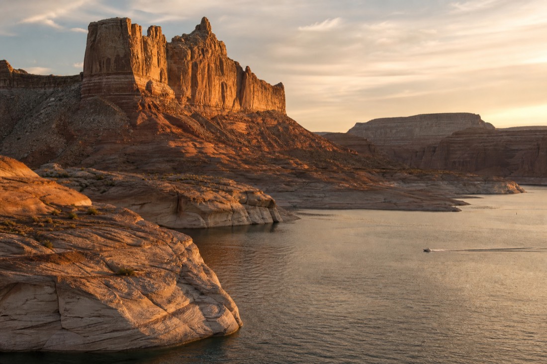 Golden-hour sandstone cliffs and open water at Lake Powell evoking a Western film backdrop