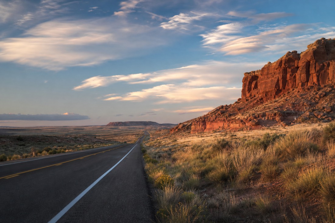 Early morning highway stretching through open Navajo Nation rangeland under a big sky