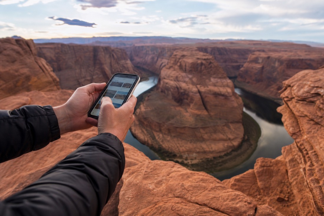 Traveler comparing tour options on a phone at a scenic desert overlook near Page Arizona