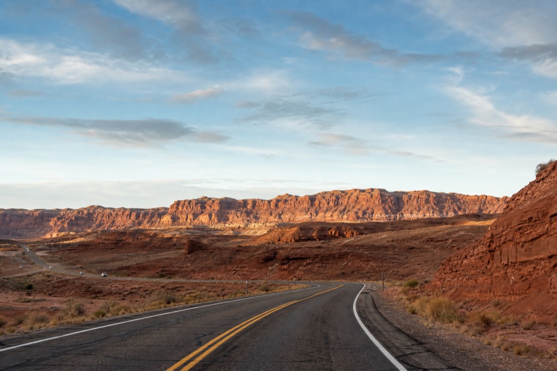 Highway 98 leaving Page Arizona with red sandstone terrain rising on the horizon