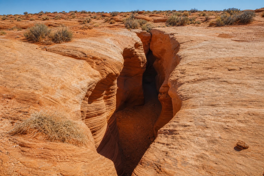 Lesser-known sandstone slot canyon entrance in open desert near Page Arizona