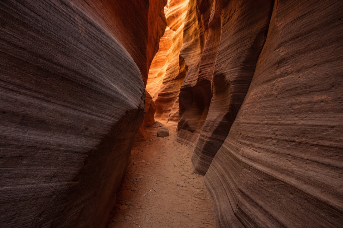 Quiet slot canyon passage with rippled sandstone walls and soft reflected light and no crowds
