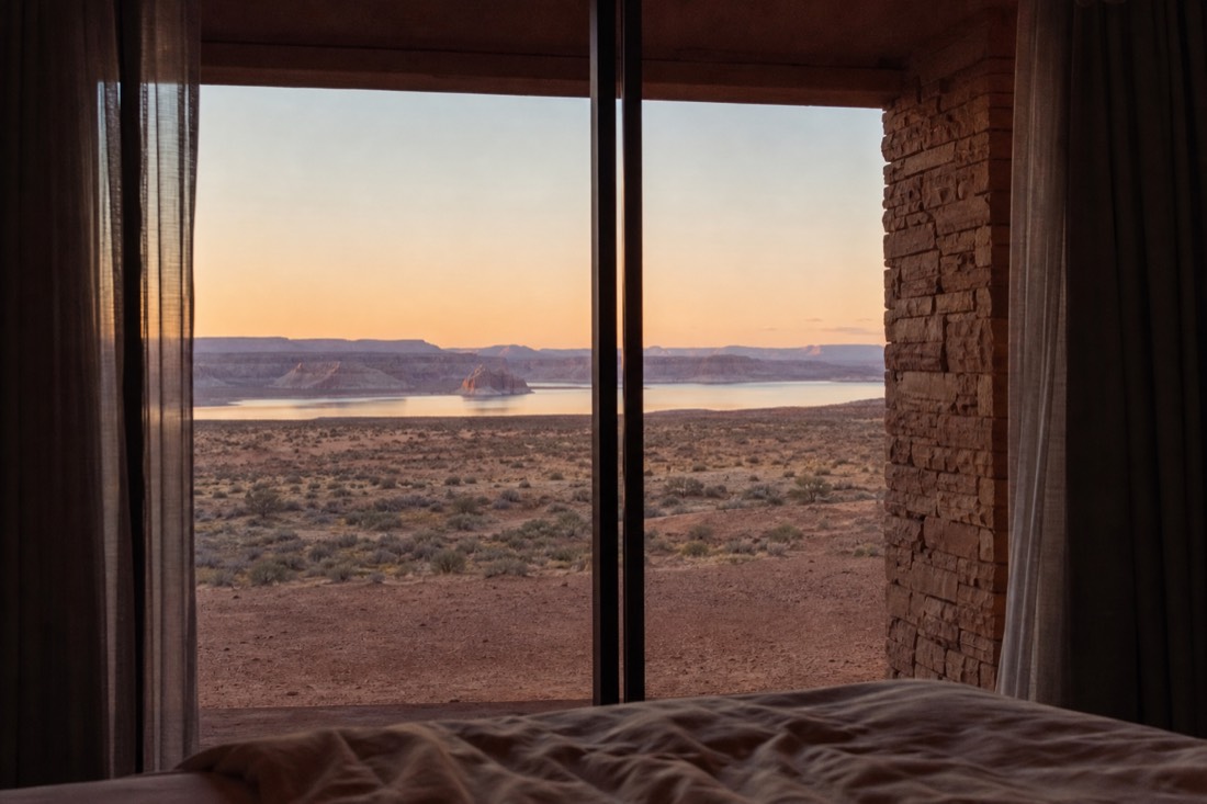 Hotel room window view of desert twilight with distant lake and cliffs