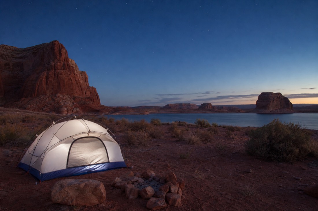 Tent campsite at dusk near Lake Powell with red cliffs and first stars