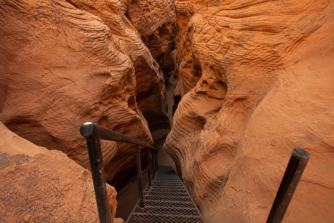 Steel stairs descending into the narrow V-shaped slot of Lower Antelope Canyon